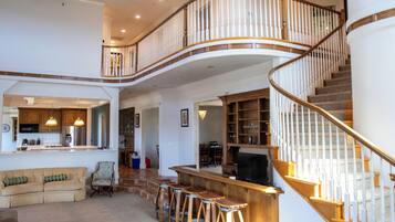 A spacious living area with a curved staircase, a kitchen, and a bar area.