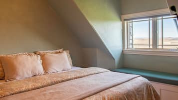 A bedroom with a bed, pillows, a window, and a sloped ceiling.