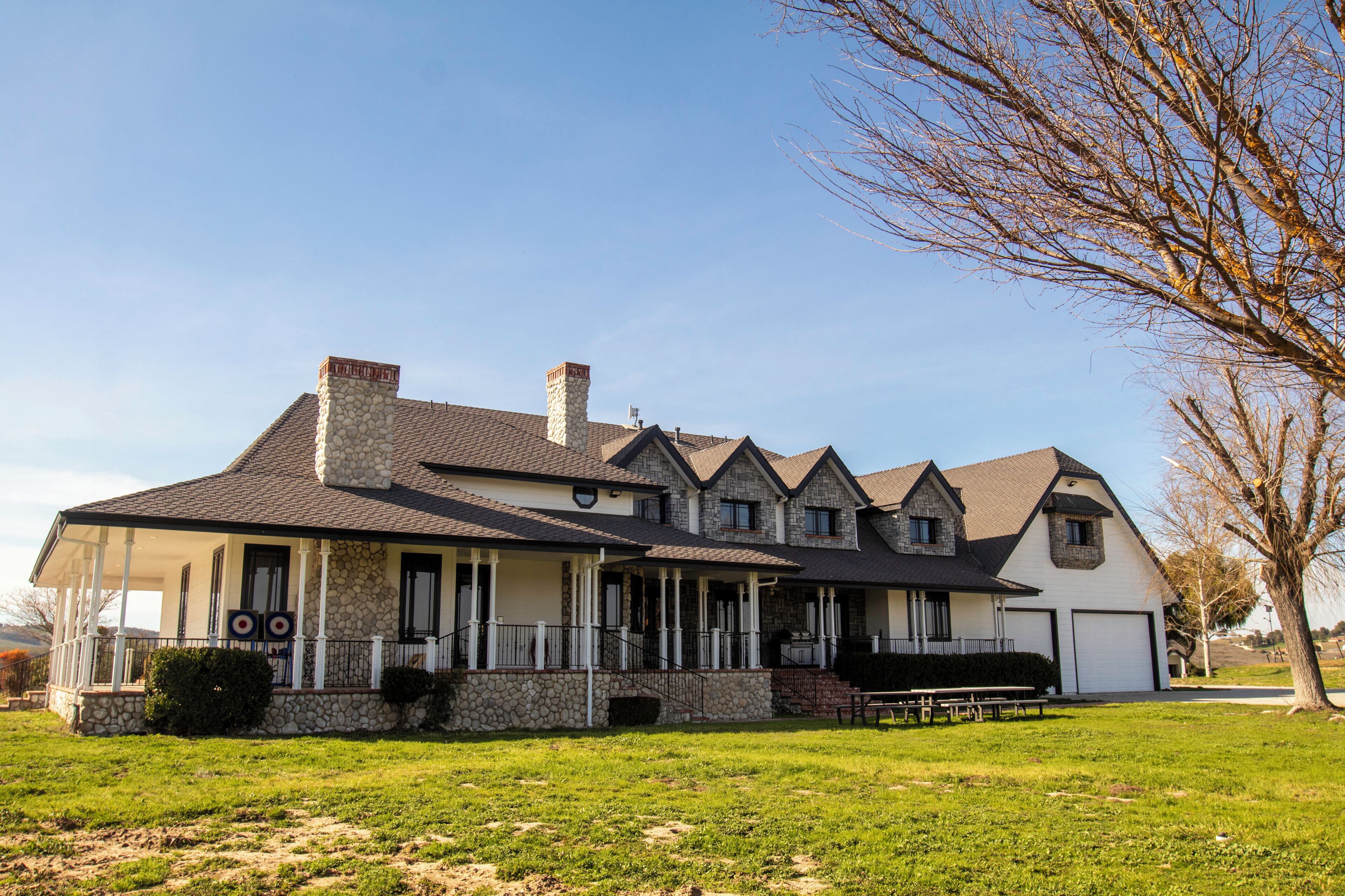 A two-story house with a stone chimney, a covered porch, and a garage.