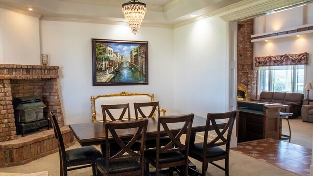 A dining area with a brick fireplace, a chandelier, and a painting of a canal scene. - Santellan Manor (Paso Robles)