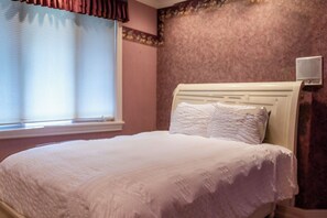 A bedroom with a bed, a window with blinds, and a wall-mounted air conditioner. - Santellan Manor (Paso Robles)