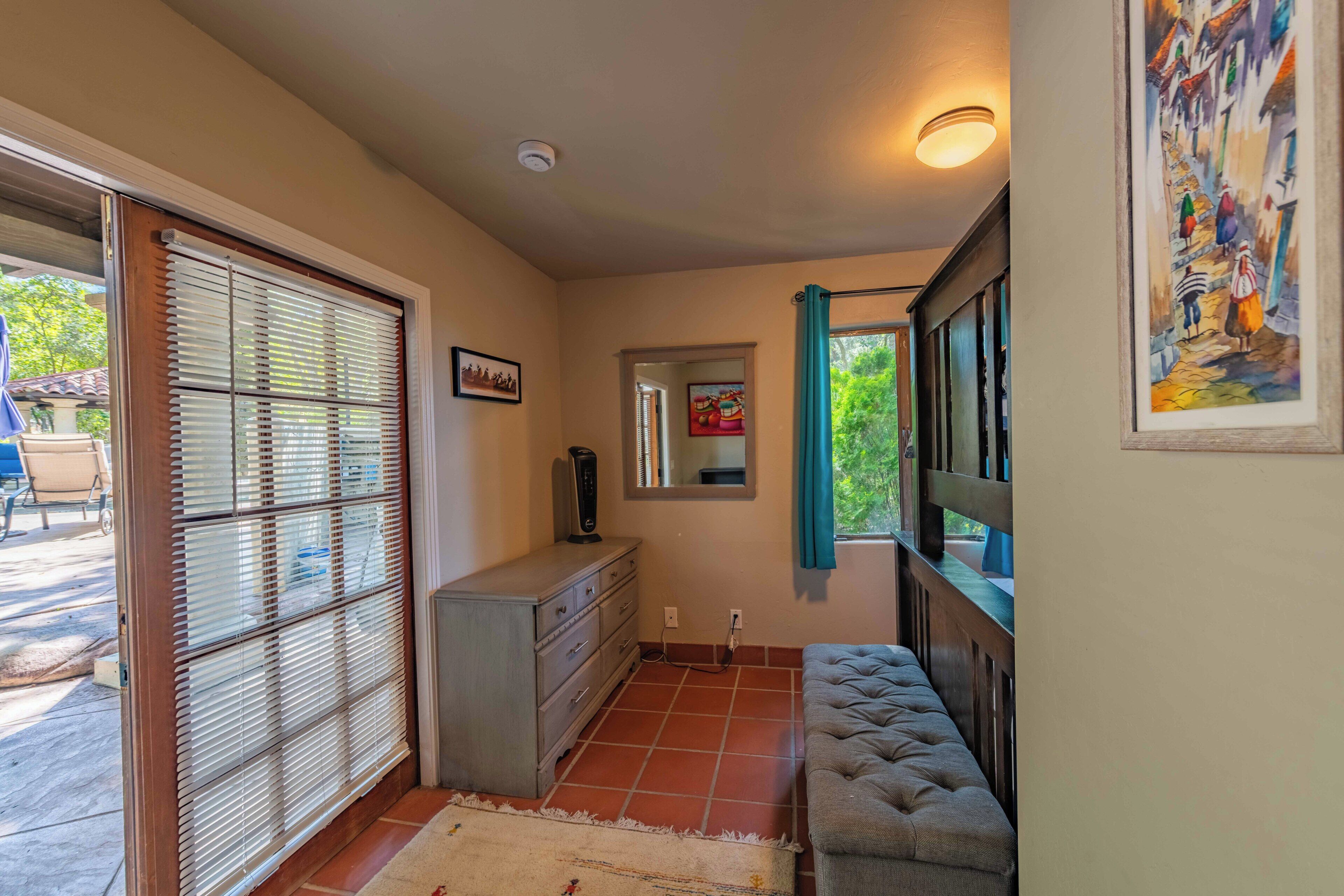A hallway with a sliding glass door, a gray sofa, a dresser, and a painting on the wall.
