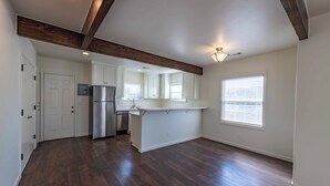 A spacious kitchen with a built-in refrigerator, a sink, and a window with blinds. - Park Street Apartment - Front Unit (Paso Robles)