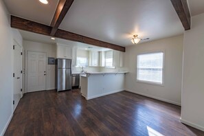 A spacious kitchen with a built-in refrigerator, a sink, and a window with blinds. - Park Street Apartment - Front Unit (Paso Robles)