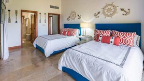 Ein Hotelzimmer mit zwei Betten, maritimer Wanddekor und einem zur benachbarten Kammer führenden Gang.