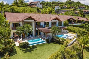 A large, two-story house with a swimming pool, surrounded by lush greenery and palm trees. - 3-BR villa with pool and views in Puerto Bahia (Sánchez)