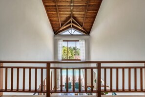 A high-ceilinged room with a wooden ceiling and a view of a pool and greenery outside. - 3-BR villa with pool and views in Puerto Bahia (Sánchez)