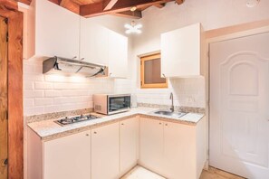 A compact kitchen with white cabinets, a microwave, a gas stove, and a window above the sink. - 3br 6 Guests  Ocean view private pool (Sánchez)