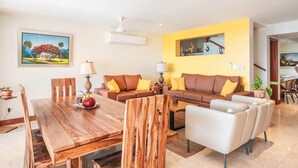 Un salón moderno con una mesa de comedor de madera, sofás marrones con cojines amarillos y una pared de acento amarilla.
