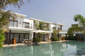 Un hotel moderno con piscina, area salotto all'aperto e palme.