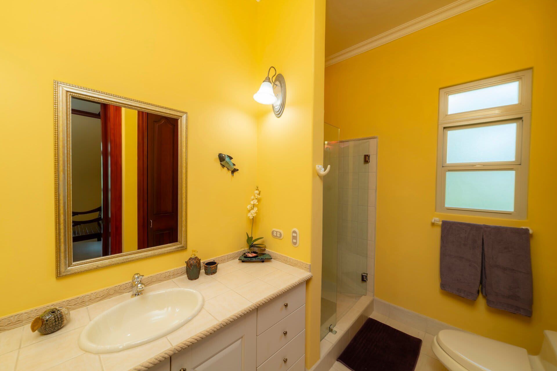 Un baño con lavamanos doble, espejo, ducha y ventana.