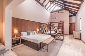 A bedroom with a large bed, wooden headboard, a wooden ladder structure, a ceiling fan, and a view of another room. - Apartment w 3br near the beach in Portillo Raa (Las Terrenas)