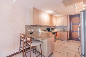 A kitchen with granite countertops, wooden cabinets, a microwave, and a refrigerator. - Apartment w 3br near the beach in Portillo Raa (Las Terrenas)
