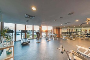 A gym with cardio equipment, weight machines, and a large window overlooking a marina. - 3BR villa 10 guests Amazing views and pool (Sánchez)