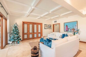 Ein geräumiges Wohnzimmer mit einem weißen Sofa, einem Weihnachtsbaum und einem großen Gemälde an der Wand.