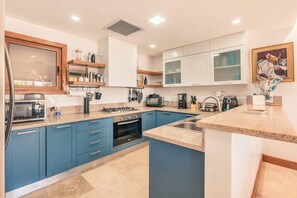 Eine moderne Küche mit blauen Schränken, einem eingebauten Ofen und einer Edelstahlspüle.