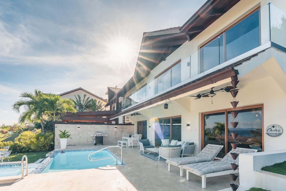 A modern house with a pool, outdoor seating, and a view of the ocean.
