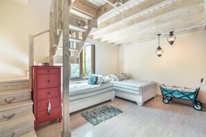 Ein Schlafzimmer mit Treppe, einem Bett, einem Babybett, einer Kommode und zwei Wandleuchten.