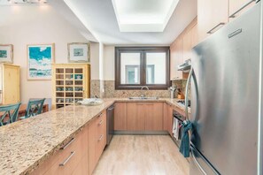 Eine Küche mit Granit Arbeitsplatten, Holzschränken, einem Edelstahlkühlschrank und einem Oberlicht.