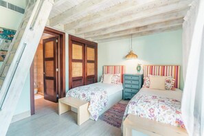 A bedroom with two beds, a bench, a dresser, and a hanging light fixture. - Family Retreat 3-Bedroom Apartment near Beach (Las Terrenas)