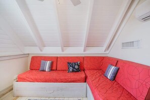 A room with a red sofa bed, a small white cabinet, and a white ceiling with exposed beams. - Family Retreat 3-Bedroom Apartment near Beach (Las Terrenas)