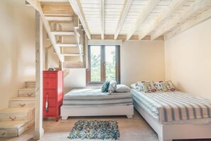 Ein Schlafzimmer mit zwei Betten, einer roten Kommode und einer Treppe.