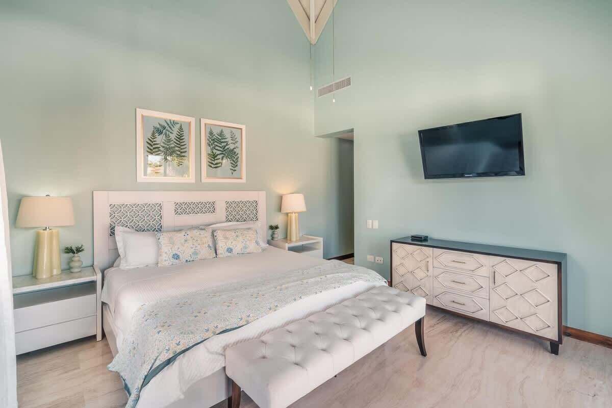 A bedroom with a bed, bedside tables, a TV, and a cabinet.