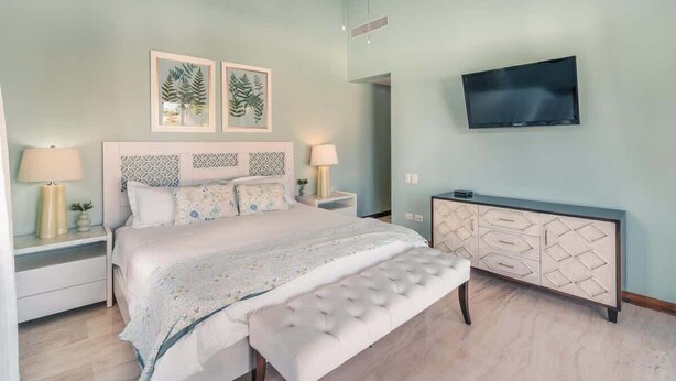 Um quarto com cama, mesas de cabeceira, televisão e armário.