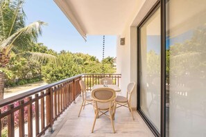 Ein Balkon mit Tisch, Stühlen und Geländer, mit Blick auf Grünflächen.