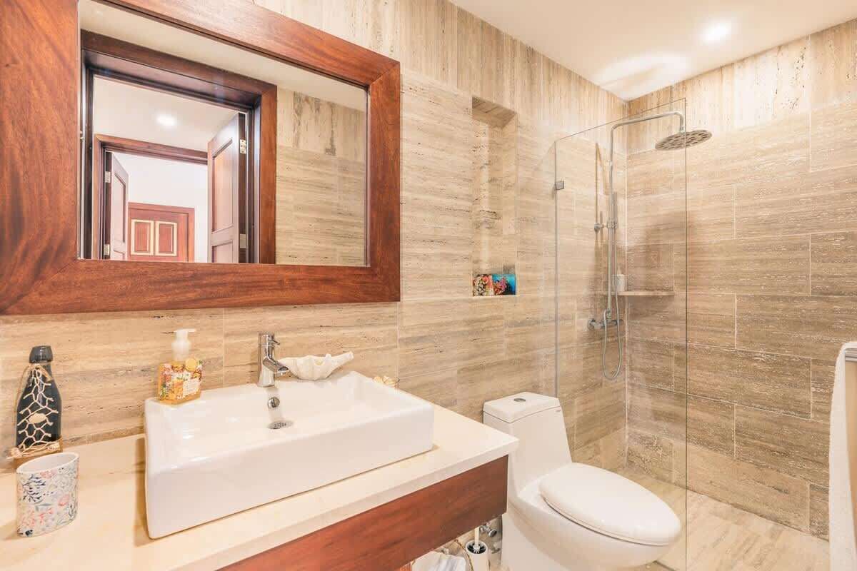 Un bagno con uno specchio grande, un lavandino, un WC e un box doccia.