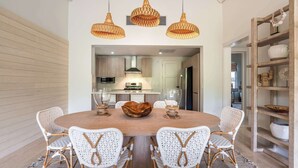 A dining area with a round table, white wicker chairs, and three wicker pendant lights. - Apt with 2BR & balcony beach access in Portillo (Las Terrenas)