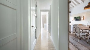 A hallway leading to a dining area with a table and chairs, a hanging light fixture, and a wall-mounted picture. - Apt with 2BR & balcony beach access in Portillo (Las Terrenas)