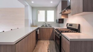 A modern kitchen with a central island, stainless steel appliances, and wooden cabinetry. - Apt with 2BR & balcony beach access in Portillo (Las Terrenas)
