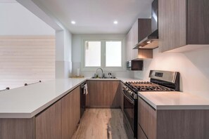 Eine moderne Küche mit einer zentralen Kochinsel, Edelstahlgeräten und Holzschränken.