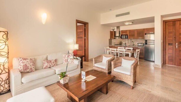 Un salon moderne comprenant un canapé, deux fauteuils, une table basse et un coin repas avec une table et des chaises.