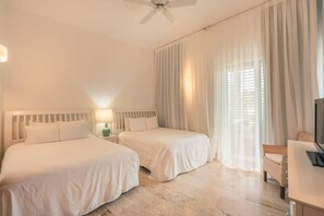 Une chambre d’hôtel avec deux lits, un ventilateur de plafond, une télévision et une fenêtre avec des rideaux.
