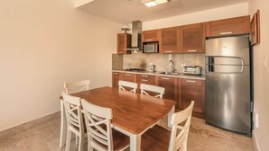 Une cuisine compacte dotée de meubles en bois, d’un réfrigérateur en acier inoxydable, d’un four à micro-ondes et d’une cuisinière à gaz.