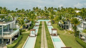 Un complexe hôtelier doté d’une piscine centrale, de plusieurs villas pour les clients et de palmiers.