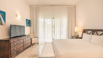 Une chambre d’hôtel avec un lit, un téléviseur posé sur une commode en bois, une lampe et une fenêtre avec des rideaux.