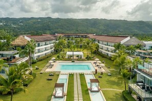 A resort with a central swimming pool, multiple buildings, and lush greenery.