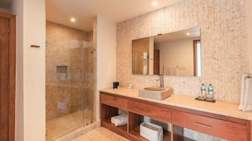 Une salle de bain moderne dotée d’une douche à parois de verre, d’un grand miroir et d’un meuble-lavabo en bois avec des tiroirs de rangement.