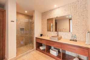 A modern bathroom with a glass-enclosed shower, a large mirror, and a wooden vanity with storage drawers.
