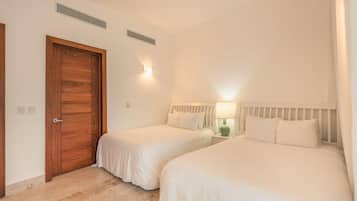 Une chambre d’hôtel avec deux lits, une porte en bois et une table de chevet avec une lampe.