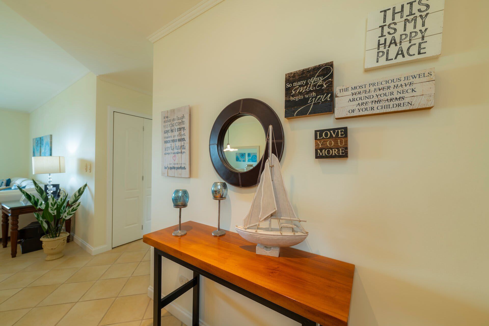 Un couloir avec une console en bois, un miroir et divers éléments de décoration murale à caractère motivant.