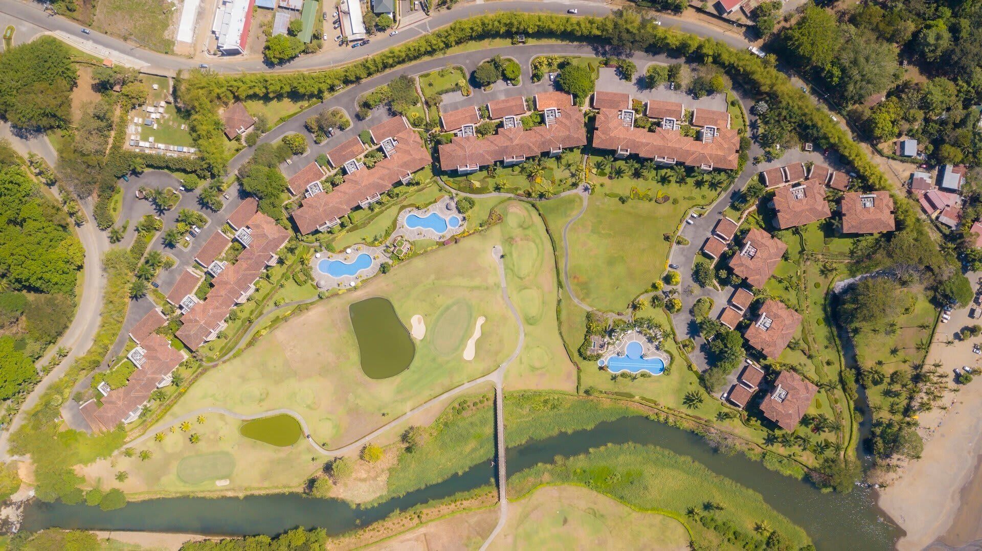 Vue aérienne d’un quartier résidentiel avec des maisons, un terrain de golf et une rivière.