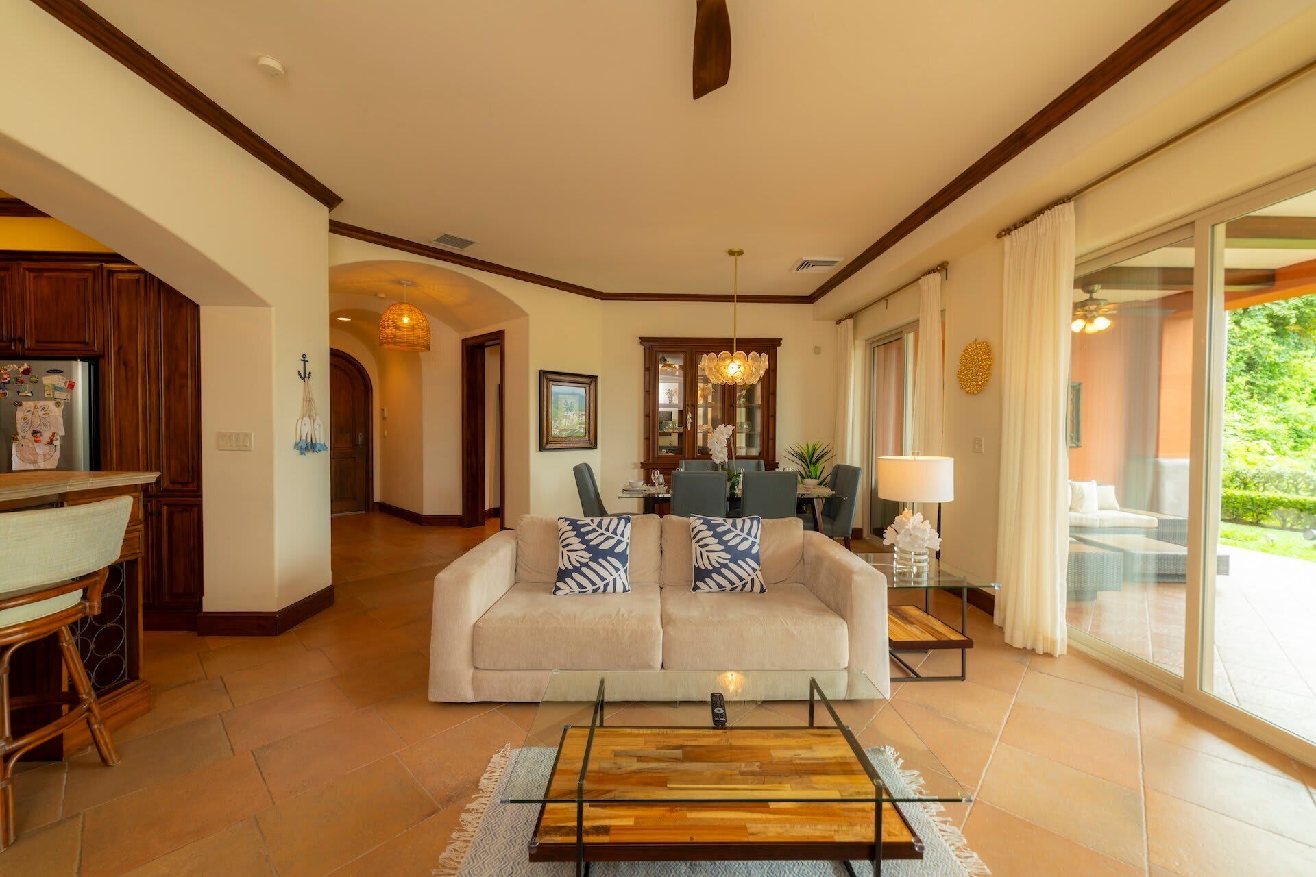 A spacious living room with a sofa, coffee table, and a dining area with a chandelier.