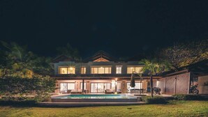 Ein zweistöckiges Haus mit einem Pool im Vordergrund.