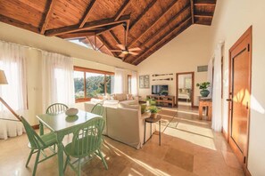 A spacious living area with a high ceiling, a dining table with chairs, a sofa, and a TV in the background. - Puerto Bahia Villa Pool, BBQ & Amazing views! (Sánchez)