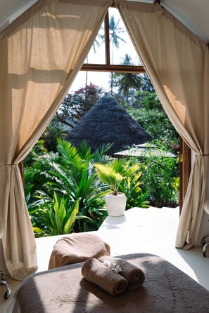 Ein Zimmer mit einem Bett, einem kleinen Tisch und einem Fenster mit Vorhängen.