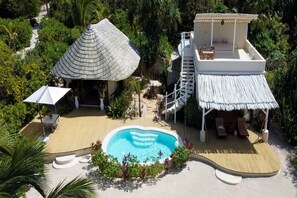 A resort with a swimming pool, a covered seating area, and a building with a thatched roof. - Indian Ocean Beachfront Sanctuary (Paje)